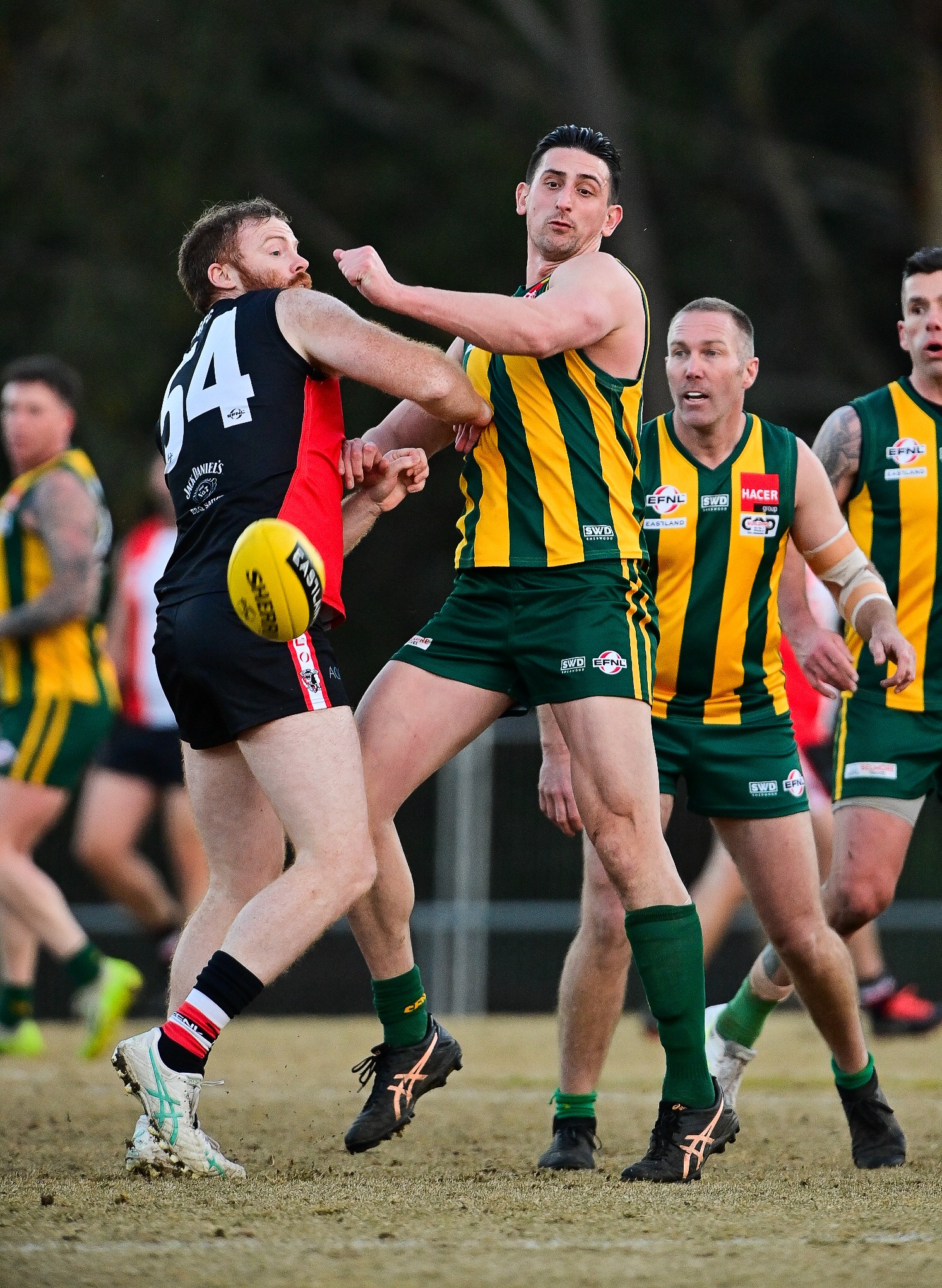 Footballer in green and gold competing in a match