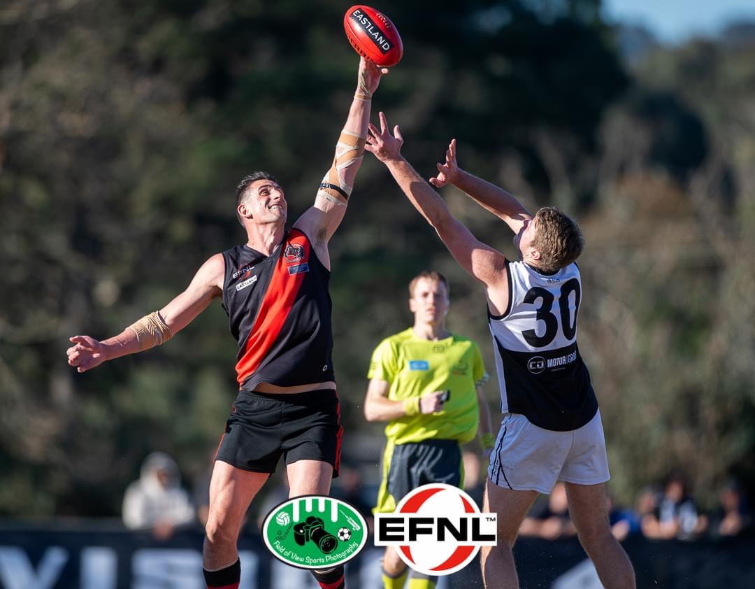 Football players contesting a ruck tap